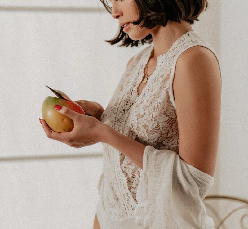 a woman in a white bodysuit holding an apple