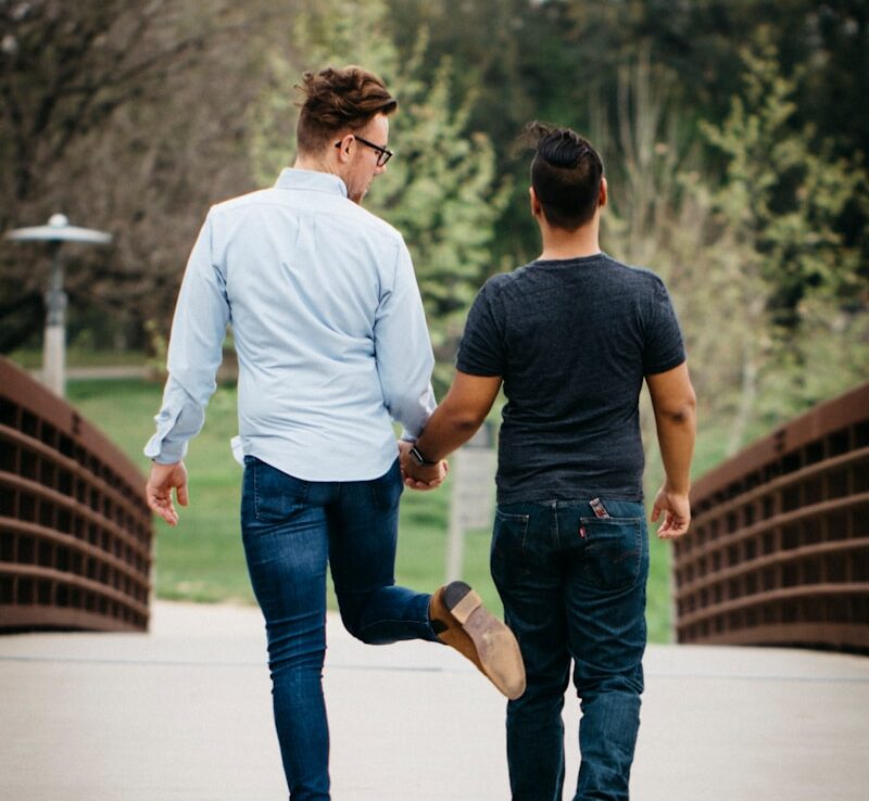 uomo in camicia bianca a maniche lunghe e jeans blu che si tiene per mano con donna in blu