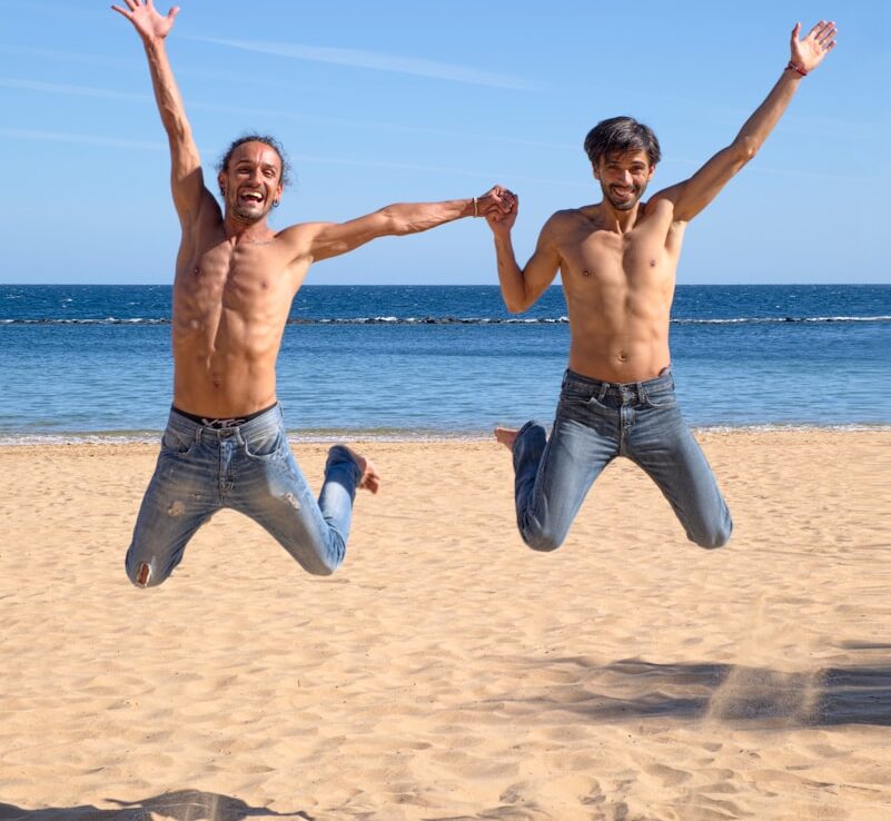 Två män hoppar över brun strandsand