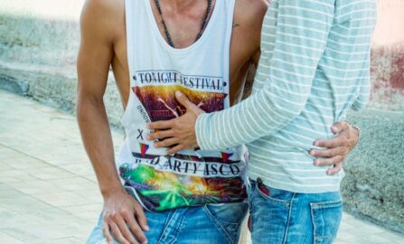 Un legame gioioso tra due amici all'aperto donna con camicia bianca a maniche lunghe e jeans blu, seduta su una panchina di cemento