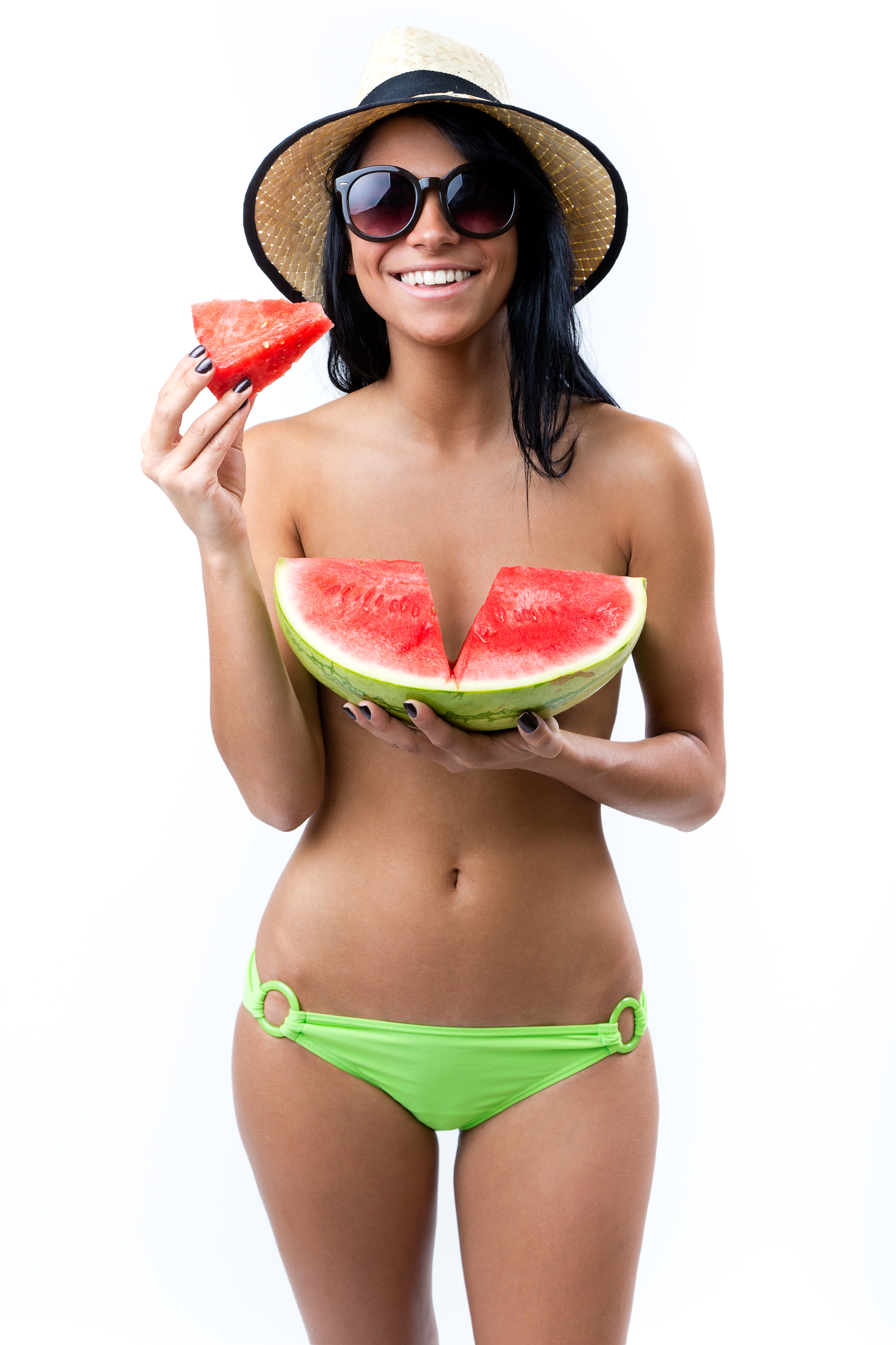 Blije vrouw in groene bikini genietend van watermeloen op een zonnige zomerdag.