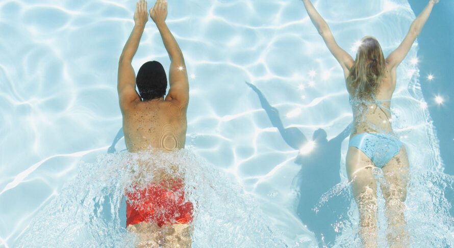 Nuoto rinfrescante in una piscina blu brillante Coppia che si gode una nuotata rinfrescante in una piscina blu scintillante in una giornata di sole.